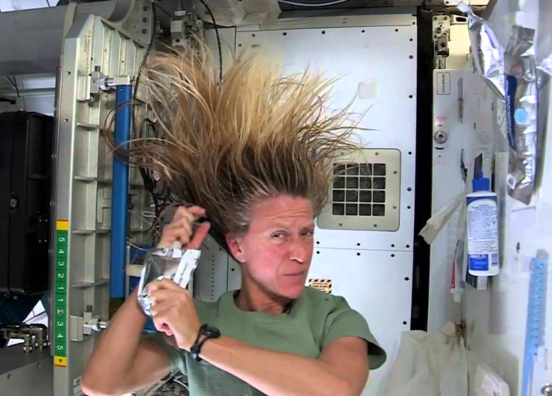 Astronaut Karen Nyberg demonstrates washing her long hair in space.