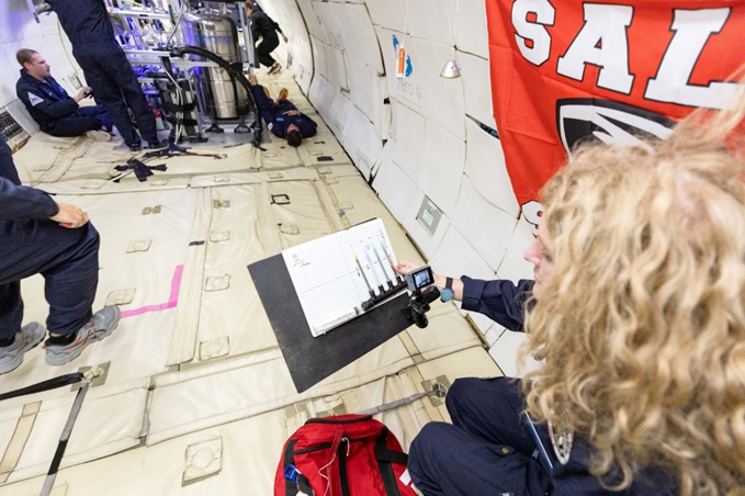 Image taken aboard parabolic flight, showing author Laura Tomlin holding the capillary apparatus mentioned later in lesson.