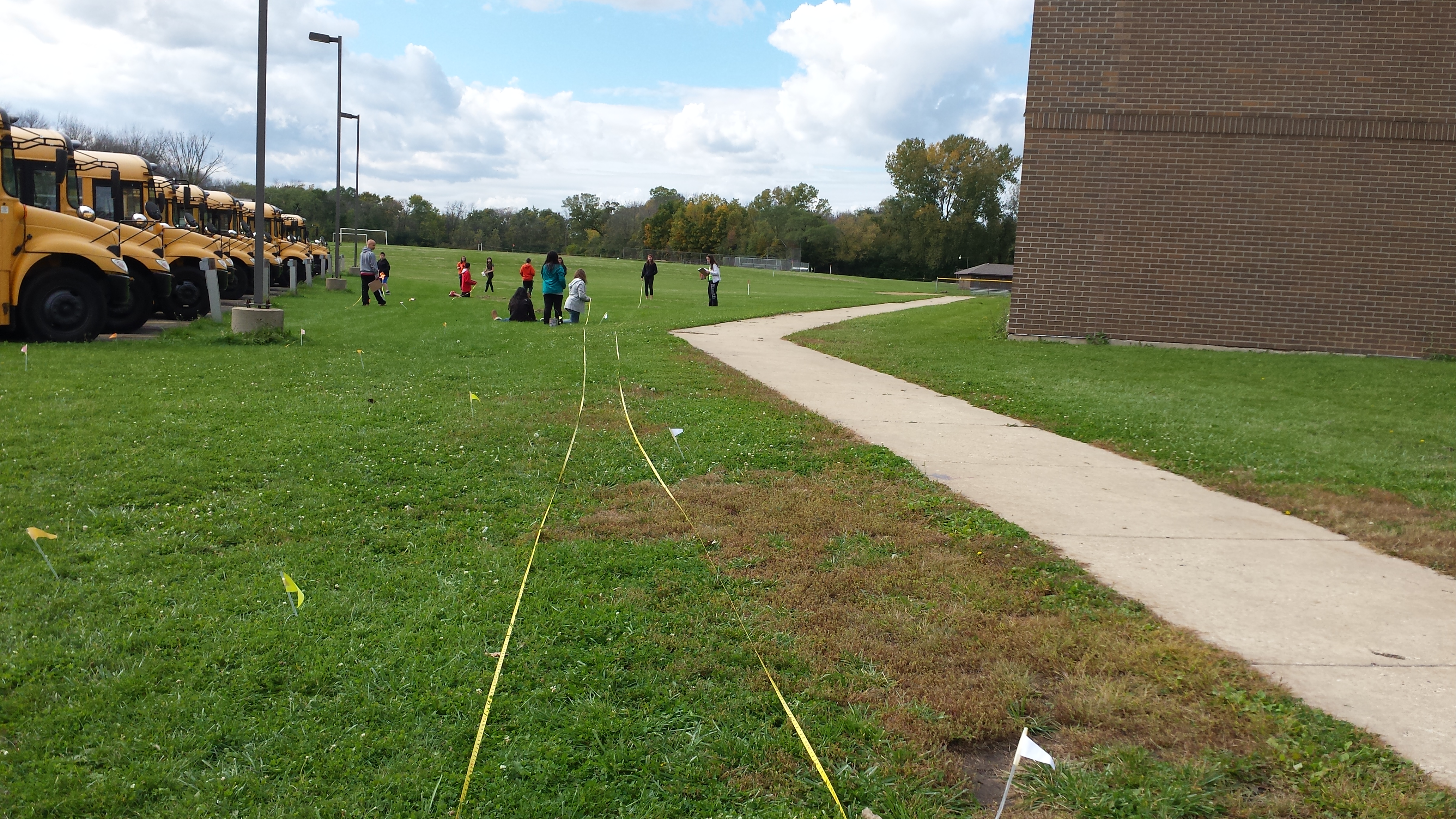 Students in a field outside their school making a to-scale solar system